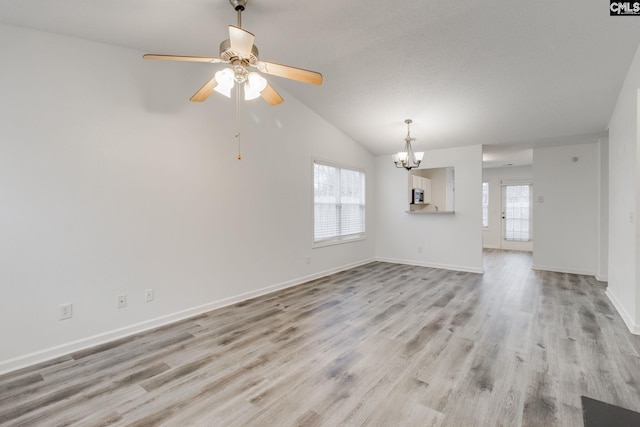 unfurnished living room with light wood-type flooring, a wealth of natural light, lofted ceiling, and baseboards