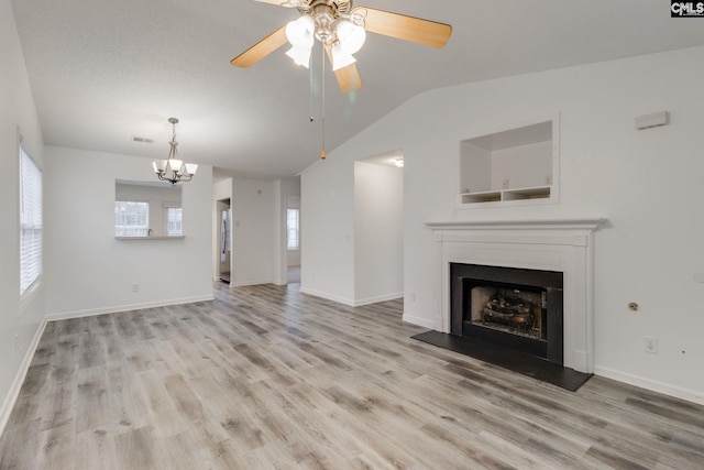 unfurnished living room featuring a fireplace with raised hearth, wood finished floors, visible vents, baseboards, and vaulted ceiling