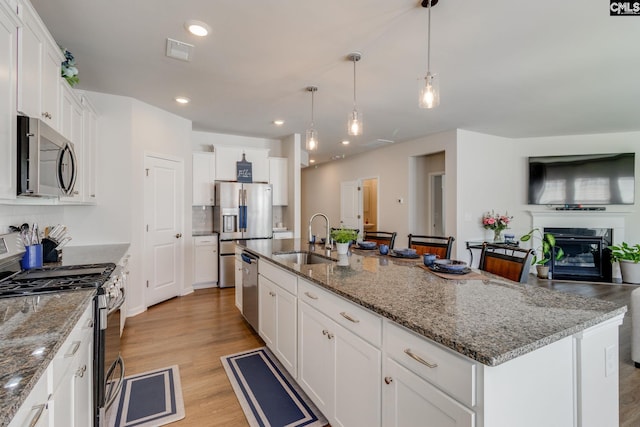 kitchen with stainless steel appliances, visible vents, light wood-style floors, white cabinets, and a sink