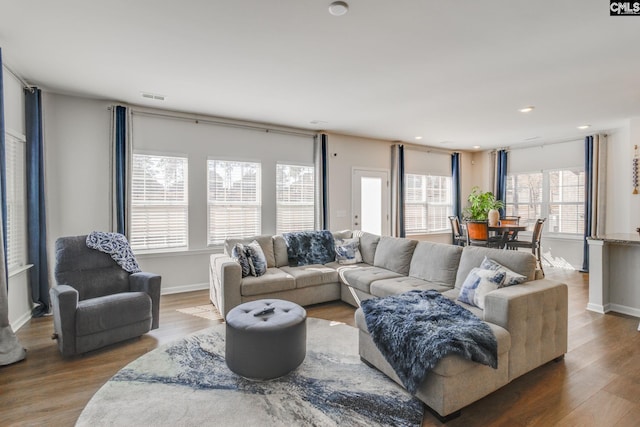 living area with recessed lighting, visible vents, baseboards, and wood finished floors