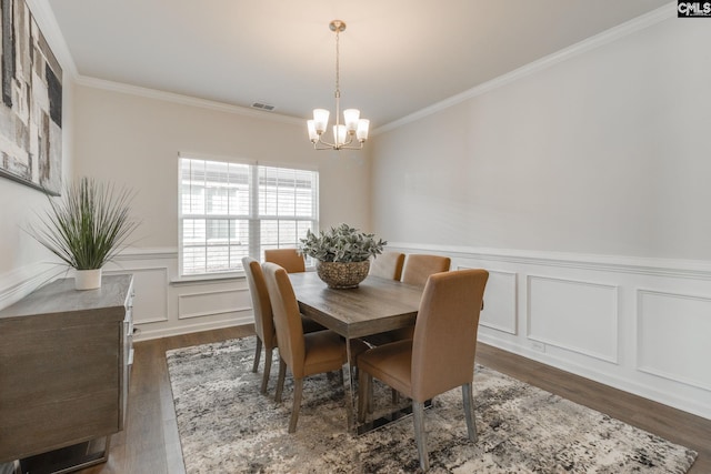 dining space with a chandelier, dark wood-type flooring, visible vents, and crown molding