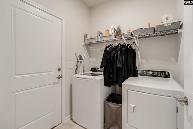 clothes washing area featuring laundry area, washing machine and clothes dryer, and light tile patterned floors