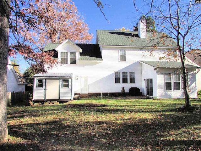 rear view of property with entry steps, a lawn, a chimney, and fence