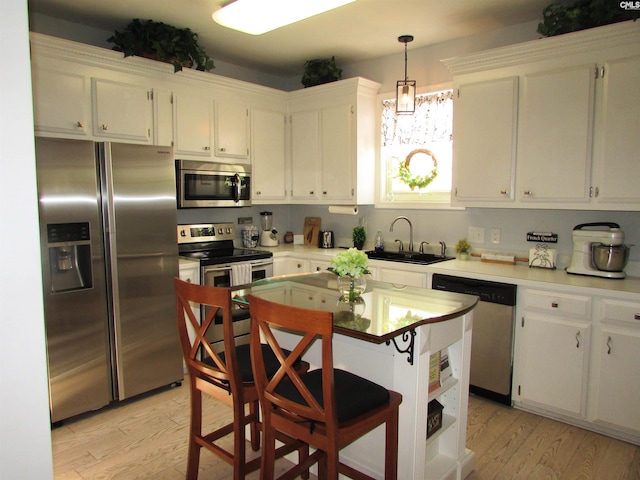 kitchen with stainless steel appliances, light countertops, light wood-style floors, white cabinetry, and a sink