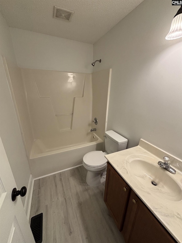 bathroom featuring a textured ceiling, toilet, wood finished floors, vanity, and visible vents