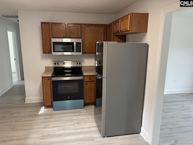 kitchen featuring stainless steel appliances, light countertops, and light wood-style flooring