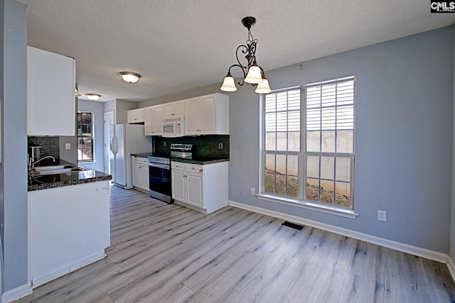 kitchen featuring white appliances, dark countertops, a sink, and visible vents