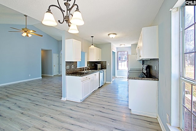 kitchen with stainless steel appliances, white cabinetry, vaulted ceiling, light wood finished floors, and dark countertops