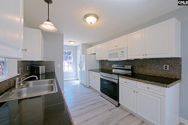 kitchen with white appliances, a sink, white cabinets, light wood-type flooring, and dark countertops