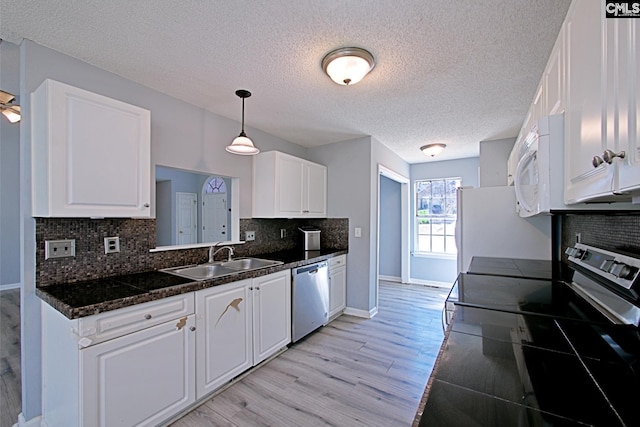 kitchen with light wood-type flooring, appliances with stainless steel finishes, white cabinets, and a sink