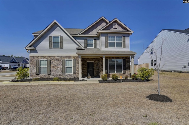 craftsman house featuring stone siding, board and batten siding, and fence