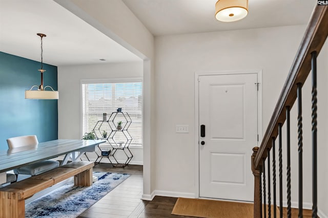 entrance foyer with dark wood-type flooring, baseboards, and stairs