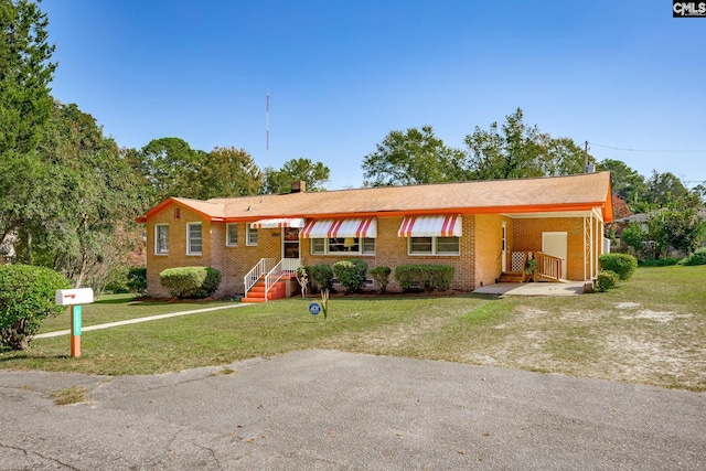 ranch-style house with driveway, brick siding, a chimney, and a front yard