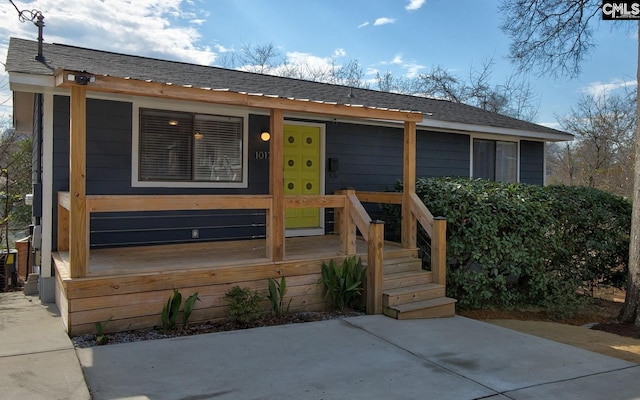 ranch-style house featuring a shingled roof and a porch