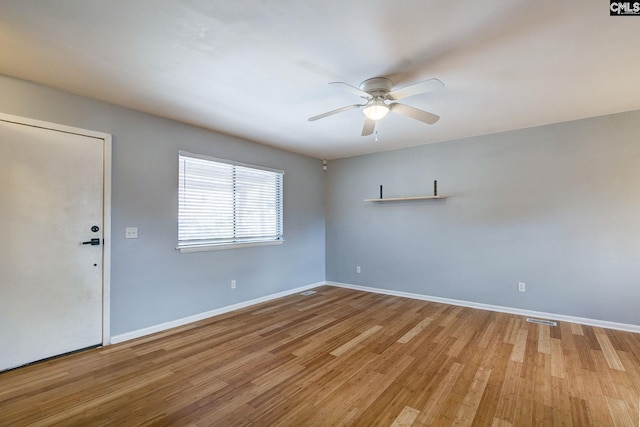 unfurnished room with a ceiling fan, visible vents, baseboards, and wood finished floors