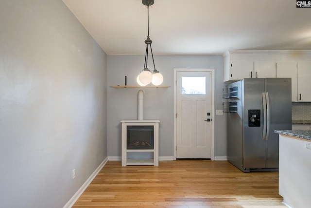 kitchen featuring baseboards, white cabinets, hanging light fixtures, stainless steel fridge with ice dispenser, and light wood finished floors