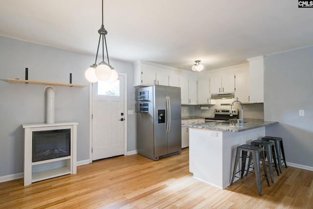 kitchen featuring tasteful backsplash, white cabinets, appliances with stainless steel finishes, a peninsula, and light wood-style floors