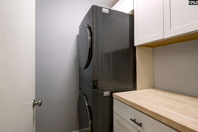 laundry area with cabinet space and stacked washer and clothes dryer