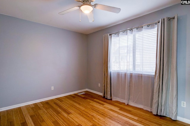 empty room with baseboards, visible vents, a ceiling fan, and light wood-style floors