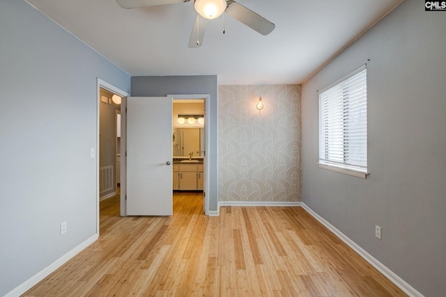 unfurnished bedroom featuring light wood-style floors, visible vents, baseboards, and a sink