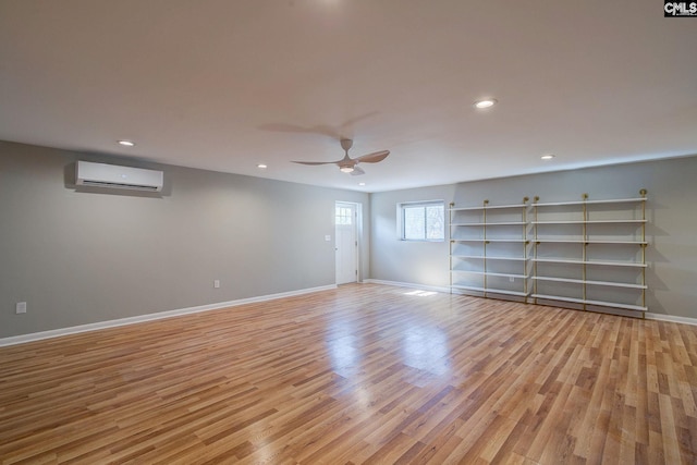 spare room with recessed lighting, a ceiling fan, baseboards, a wall mounted AC, and light wood-type flooring