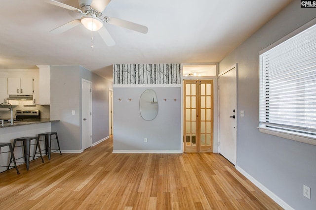 living room featuring light wood-type flooring, baseboards, and a ceiling fan