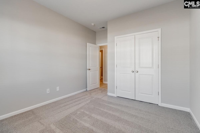 unfurnished bedroom featuring light carpet, visible vents, baseboards, and a closet