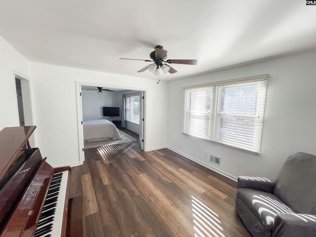 bedroom featuring a ceiling fan, dark wood-style flooring, visible vents, and baseboards