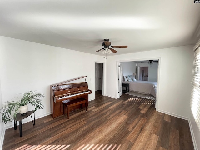 interior space with a ceiling fan, dark wood finished floors, and baseboards