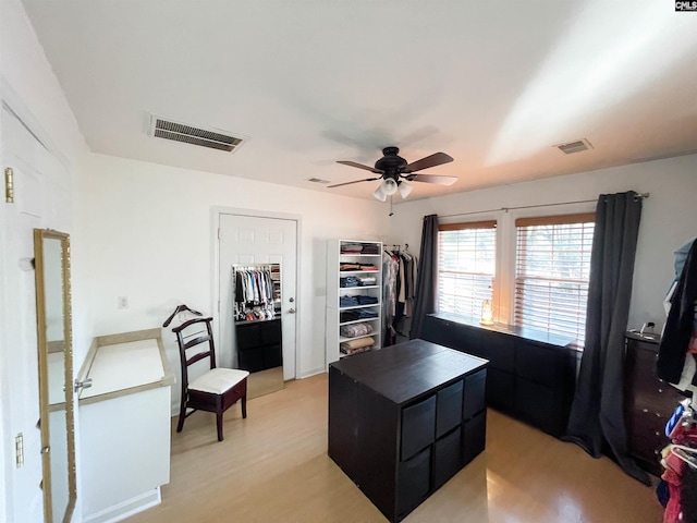 home office with a ceiling fan, light wood-type flooring, and visible vents