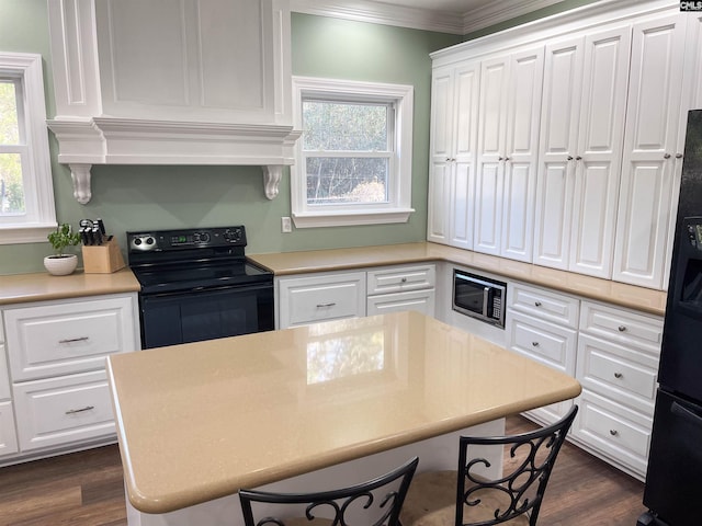 kitchen with black appliances, light countertops, white cabinetry, and crown molding