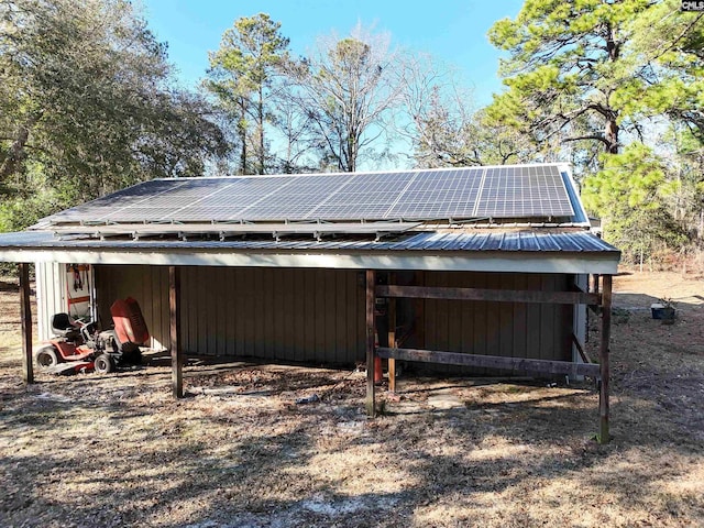 exterior space with roof mounted solar panels, metal roof, a carport, and an outbuilding