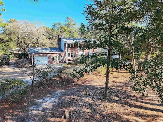 rear view of house featuring a garage and a chimney