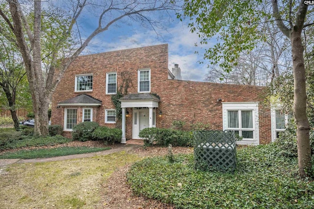 view of front of house featuring brick siding and a chimney