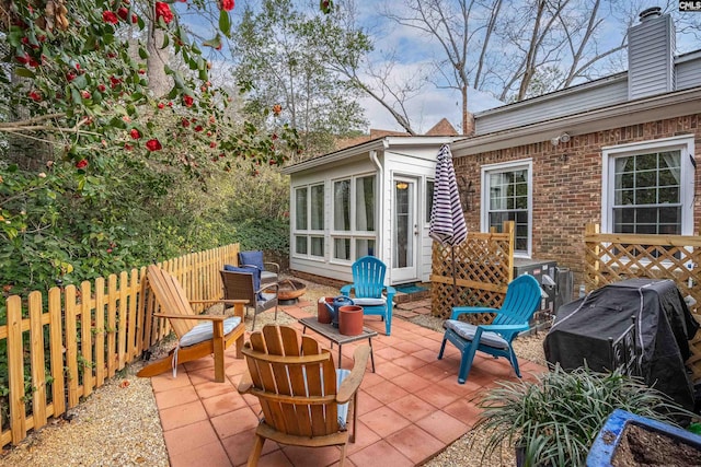 view of patio with a fire pit, a fenced backyard, and a sunroom