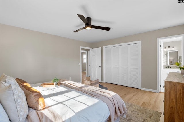 bedroom with light wood finished floors, a closet, ensuite bathroom, a ceiling fan, and baseboards