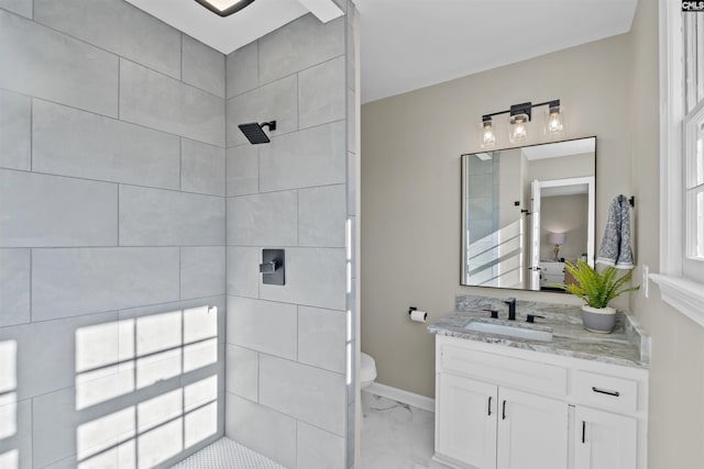 full bathroom featuring marble finish floor, toilet, vanity, tiled shower, and baseboards