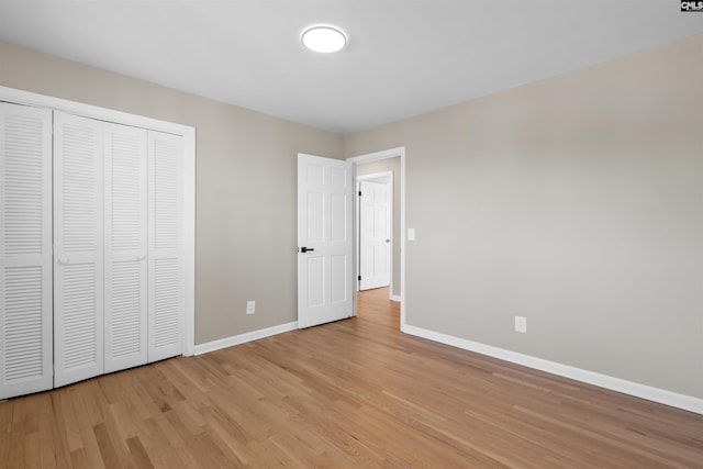 unfurnished bedroom with light wood-style floors, a closet, and baseboards