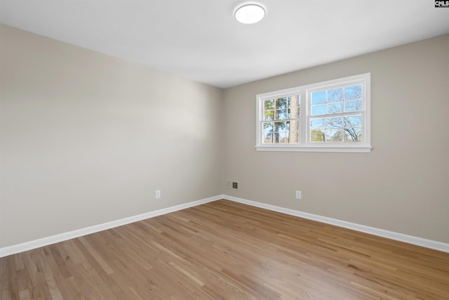 spare room featuring light wood-type flooring, visible vents, and baseboards