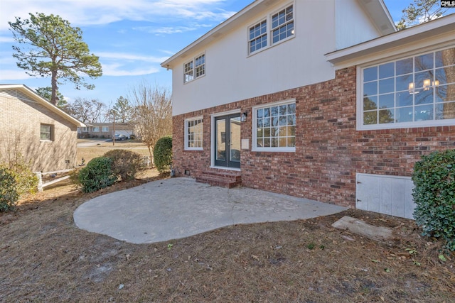 rear view of property with entry steps, a patio area, french doors, and brick siding