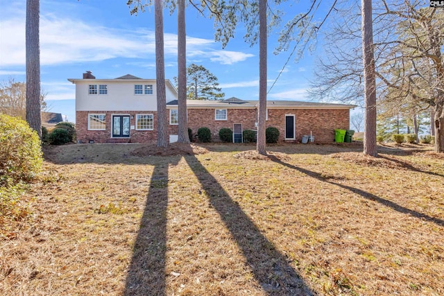 view of front of home with crawl space, a chimney, and brick siding