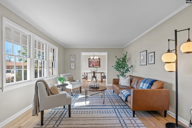 living room with light wood-style floors, baseboards, a notable chandelier, and ornamental molding