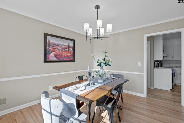 dining space with light wood-style floors, a chandelier, crown molding, and baseboards