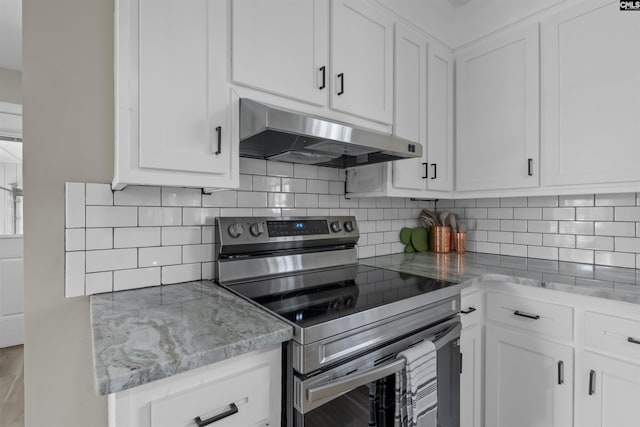 kitchen with stainless steel electric stove, backsplash, white cabinets, light stone countertops, and under cabinet range hood