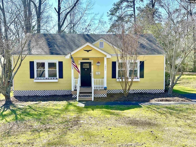 bungalow-style home featuring a front yard and roof with shingles