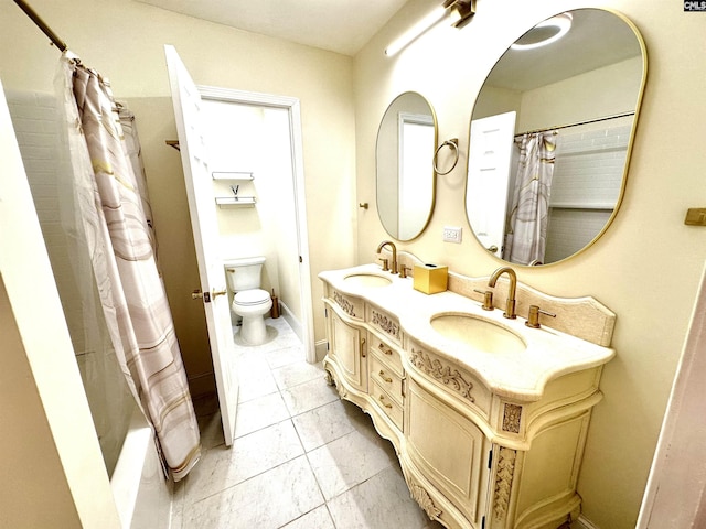 full bathroom featuring toilet, double vanity, baseboards, and a sink