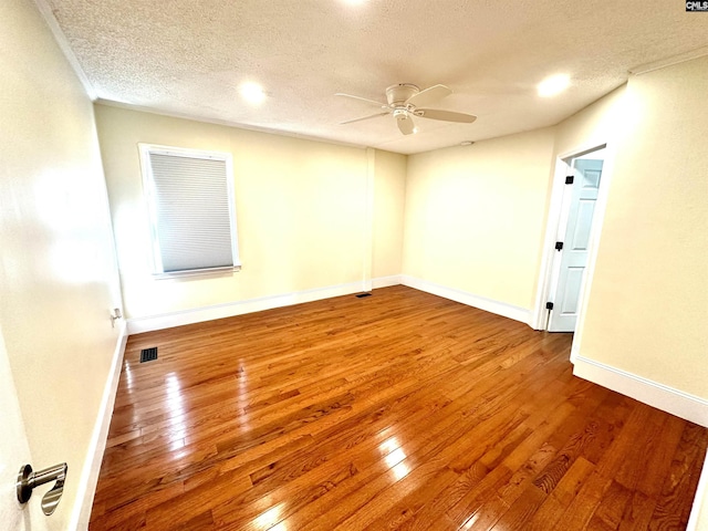 unfurnished room featuring visible vents, hardwood / wood-style floors, a ceiling fan, a textured ceiling, and baseboards