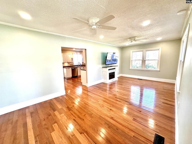 unfurnished living room with light wood finished floors, a fireplace, baseboards, and crown molding