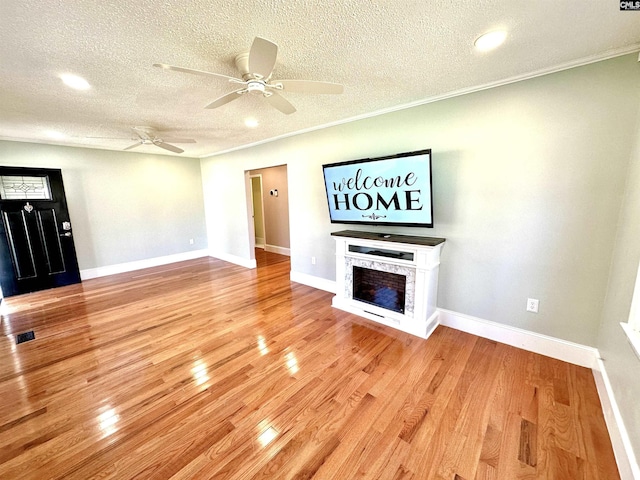 unfurnished living room featuring light wood-type flooring, baseboards, visible vents, and a stone fireplace