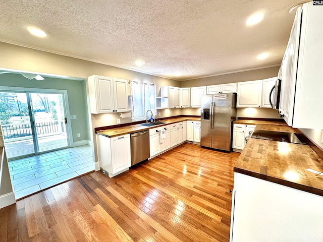 kitchen featuring stainless steel appliances, butcher block countertops, a sink, and light wood-style floors